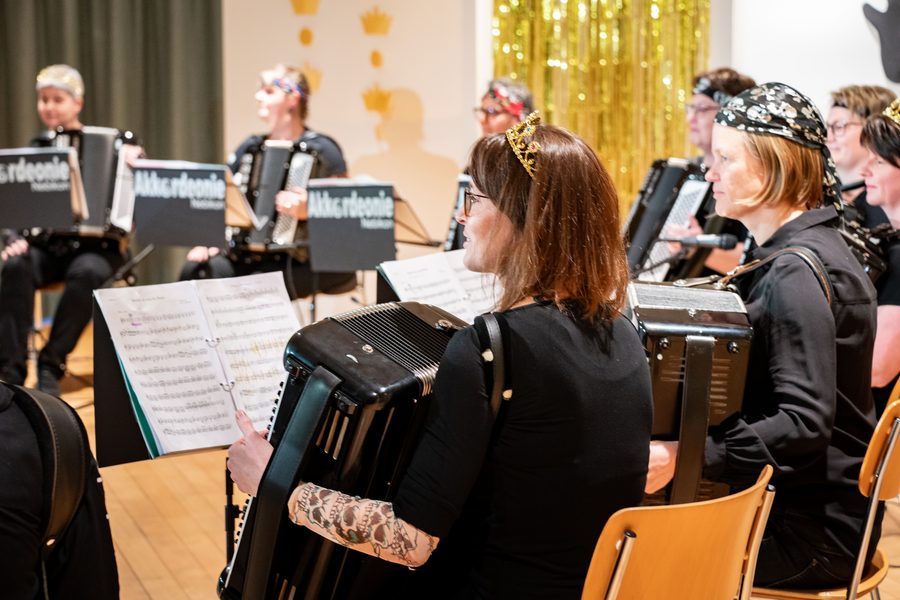 Spielerinnen der Akkordeonie mit Krönchen und Kopftüchern während eines Konzerts, Blick über die Schulter auf die Noten
